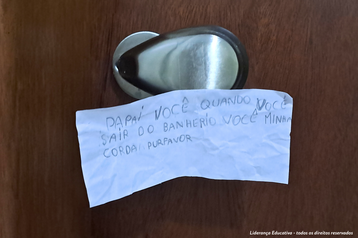 Alfabetização, um bilhete colado na maçaneta da porta do banheiro, com recado da filha para o pai.