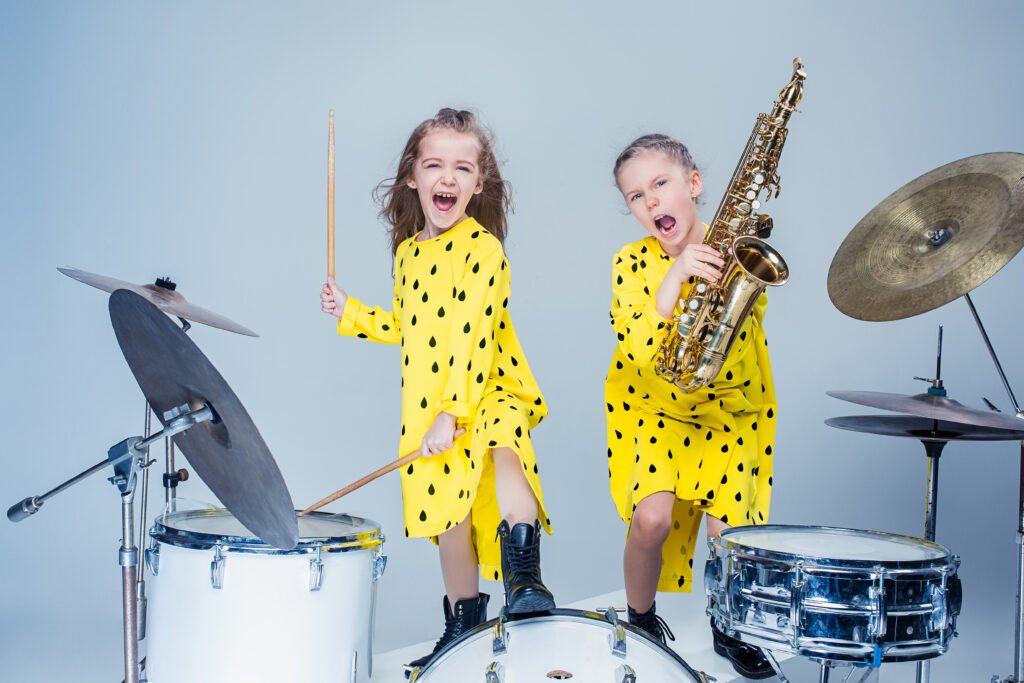 Duas meninas fazendo musicalização infantil, tocando instrumentos.